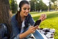 Beautiful young woman student in the park listening music with headphones using mobile phone. Royalty Free Stock Photo