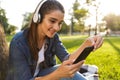 Beautiful young woman student in the park listening music with headphones using mobile phone. Royalty Free Stock Photo