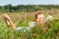 Beautiful young woman-student reading a book lying on the grass. Pretty girl outdoors in summertime Royalty Free Stock Photo