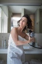 Beautiful young woman styling her her in her bathroom