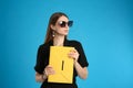 Beautiful young woman with stylish yellow bag on light blue background Royalty Free Stock Photo