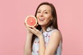 Beautiful young woman in summer clothes hold in hand half of fresh ripe grapefruit isolated on pink pastel wall Royalty Free Stock Photo