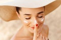 Beautiful Young woman with sun cream on face. Girl holding sunscreen bottle on the beach Royalty Free Stock Photo