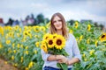 Beautiful young woman on sunflower field with bouquet flowers. Happy girl on summer sunset day. Royalty Free Stock Photo