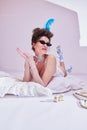 Beautiful young woman in sunglasses lying on bed in vintage lingerie. Eyewear brand ad, featuring modern frames with Royalty Free Stock Photo