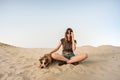 Beautiful young woman in sunglasses rests with dog on sandy beach or desert. Girl in hiking casual clothes and staffordshire terr Royalty Free Stock Photo