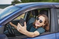 Beautiful young woman in sunglasses smiling communicating video call using smartphone while sitting in car Royalty Free Stock Photo