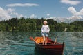 beautiful young woman in sunglasses standing in boat at tranquil mountain lake Royalty Free Stock Photo