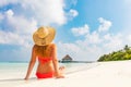 Beautiful young woman in sunhat sitting relaxed on tropical beach in Maldives Royalty Free Stock Photo