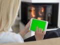 Young woman using tablet computer in front of fireplace Royalty Free Stock Photo