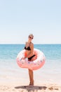 Beautiful young woman in swimming pool swims on inflatable ring donut and has fun with glass of cocktail on vacation Royalty Free Stock Photo