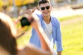 Beautiful young woman taking photo of her boyfriend in the park. Royalty Free Stock Photo