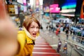 Beautiful young woman taking a selfie with her smartphone on Times Square Royalty Free Stock Photo