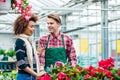 Beautiful young woman talking with friendly worker at flower shop Royalty Free Stock Photo