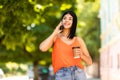 Beautiful young woman talking on mobile phone and holding a coffee to-go in disposable paper cup Royalty Free Stock Photo