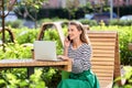 Beautiful young woman talking on mobile phone while using laptop outdoors Royalty Free Stock Photo