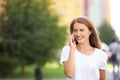 Beautiful young woman talking on mobile phone while walking outdoors Royalty Free Stock Photo