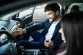 Beautiful young woman is talking to handsome car dealership worker while choosing a car in dealership Royalty Free Stock Photo