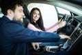 Beautiful young woman is talking to handsome car dealership worker while choosing a car in dealership Royalty Free Stock Photo