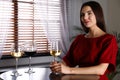 Beautiful young woman tasting luxury wine at table