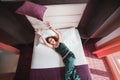 Young woman throwing a pillow lying on a big bed Royalty Free Stock Photo