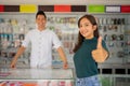 beautiful young woman with thumbs up standing against the background of a smartphone shop Royalty Free Stock Photo