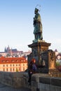 Beautiful young woman is touching the bronze plaque on Charles bridge for good luck. Prague. Royalty Free Stock Photo