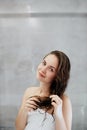 Hair and body care. Woman touching wet hair and smiling while looking in the mirror. Portrait of girl  in bathroom applying condit Royalty Free Stock Photo