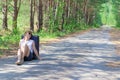 Young woman tourist with a suitcase on a forest road on a summer sunny day against the backdrop of green trees. Close-up. Selectiv Royalty Free Stock Photo