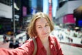 Beautiful young woman tourist taking selfie on Times Square on sunny summer day, downtown Manhattan. Famous street of New York Royalty Free Stock Photo