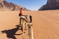 Beautiful young woman tourist in white dress riding on camel in wadi rum desert, Jordan