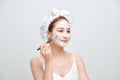 Beautiful young woman with towel wrapped around her head applying face mask Royalty Free Stock Photo