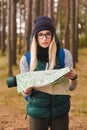 A beautiful young woman with travel map and backpack in pine plantations.