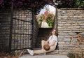 Beautiful young woman traveler girl in a white shirt with a hat in his hands sitting on the steps at the entrance to a house in a Royalty Free Stock Photo