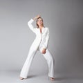 beautiful young woman in a trendy white suit stands in a dynamic pose, Royalty Free Stock Photo