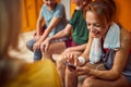 Beautiful young woman typing on smartphone, getting ready for workout, sitting in gym locker room with senior man and women Royalty Free Stock Photo