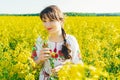 Beautiful young woman in Ukrainian embroidered standing in a field of yellow flowers Royalty Free Stock Photo