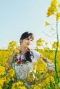 Beautiful young woman in Ukrainian embroidered standing in a field of yellow flowers Royalty Free Stock Photo