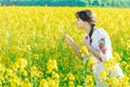 Beautiful young woman in Ukrainian embroidered standing in a field of yellow flowers Royalty Free Stock Photo