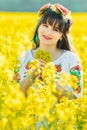 Beautiful young woman in Ukrainian embroidered standing in a field of yellow flowers Royalty Free Stock Photo