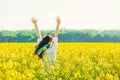 Beautiful young woman in Ukrainian embroidered standing in a field of yellow flowers.back view Royalty Free Stock Photo