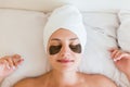 Beautiful young woman with under eye patches in bathrobe lying in bed. Happy girl taking care of herself. Beauty skincare and Royalty Free Stock Photo