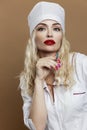 A beautiful young woman in the uniform of a nurse with a syringe in her hand. Sexy blonde with red lips. Compulsory vaccination. Royalty Free Stock Photo