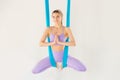 Beautiful young woman in uniform sport namaste prayer mudra aero fly yoga on blue hammock in white class