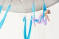 Beautiful young woman in uniform trainer shows asana stretching aero fly yoga on blue hammock in white class