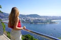 Beautiful young woman on Urca Hill belvedere looks Rio de Janeiro cityscape, Brazil