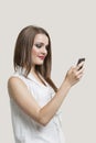 Beautiful young woman using cell phone against gray background Royalty Free Stock Photo