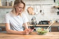 Beautiful young woman using cell phone while making salad in the kitchen. Healthy food. vegetable salad. Diet. Healthy lifestyle. Royalty Free Stock Photo