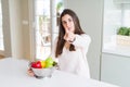 Beautiful young woman using colander to wash and clean vegatables pointing with finger to the camera and to you, hand sign,