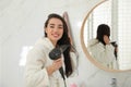 Beautiful young woman using hairdryer in bathroom Royalty Free Stock Photo